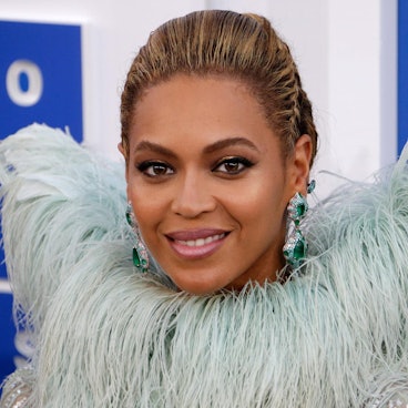 Beyoncé lacht für die Fotografen. Sie trägt eine extravagante Federboa.