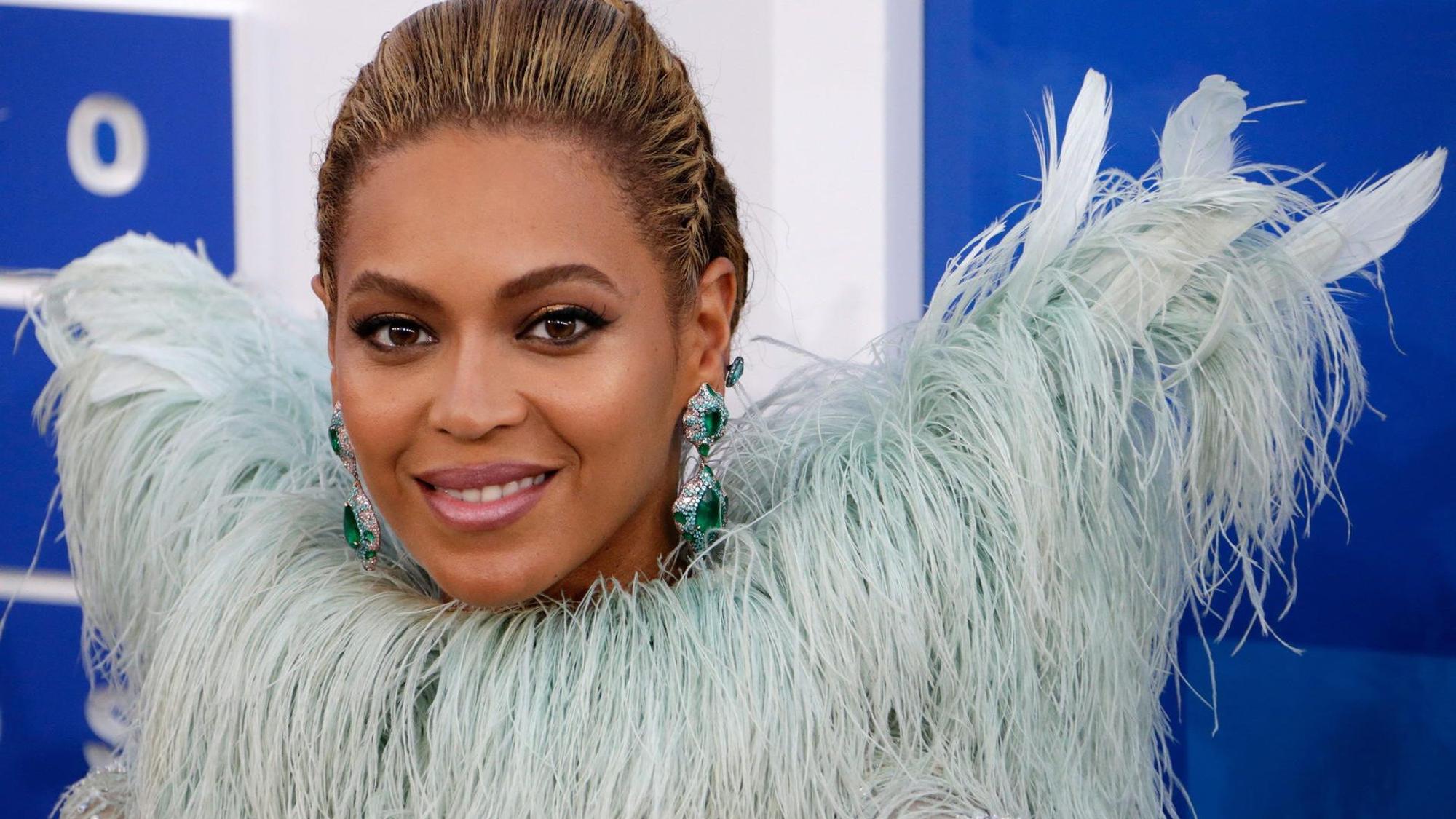 Beyoncé lacht für die Fotografen. Sie trägt eine extravagante Federboa.