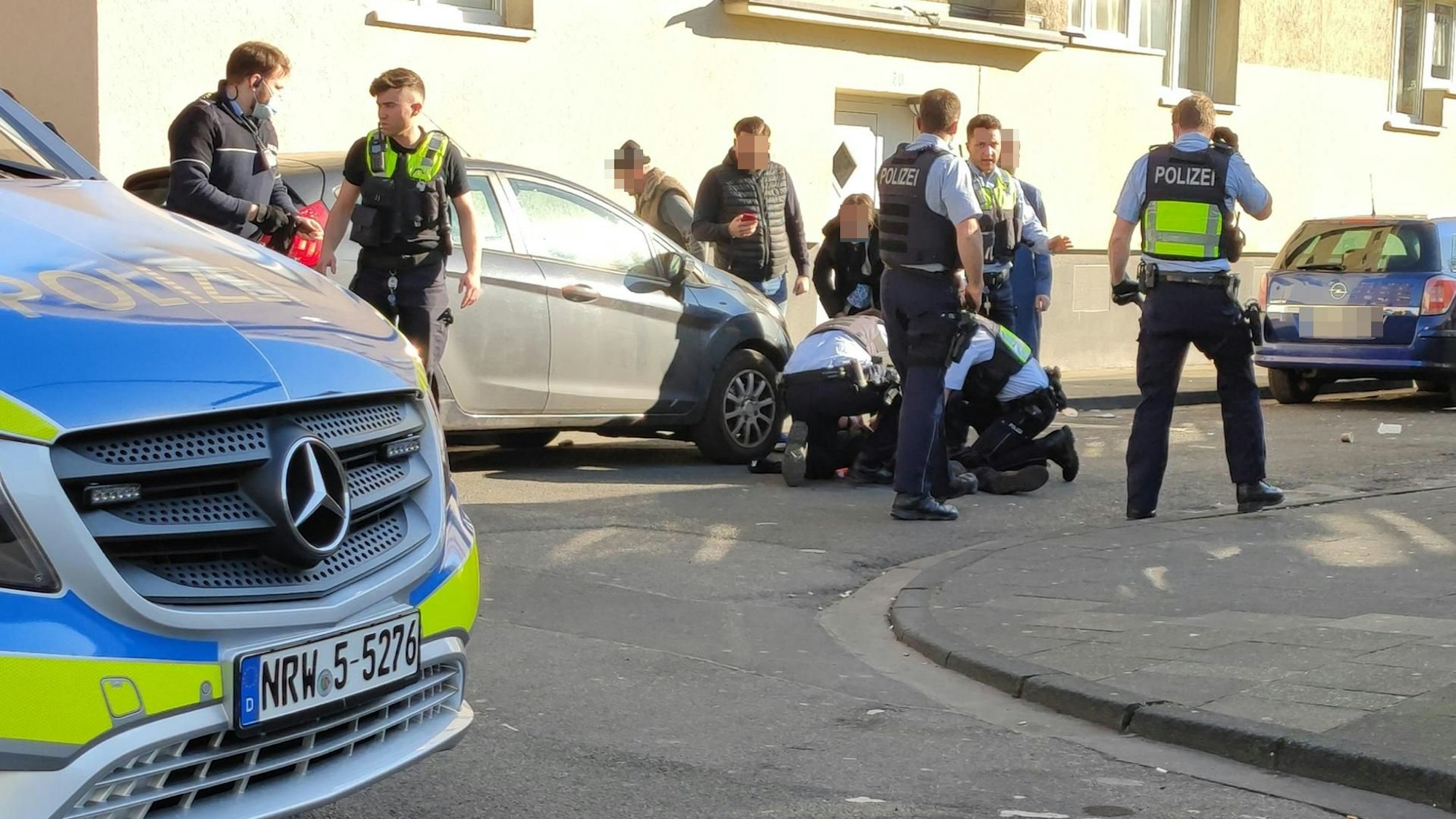 Polizisten kümmern sich in Höhenberg um das schwerverletzte Opfer.