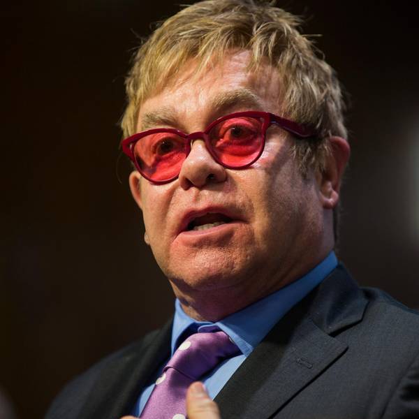 Elton John mit roter Brille bei einem öffentlichen Auftritt.