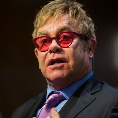 Elton John mit roter Brille bei einem öffentlichen Auftritt.