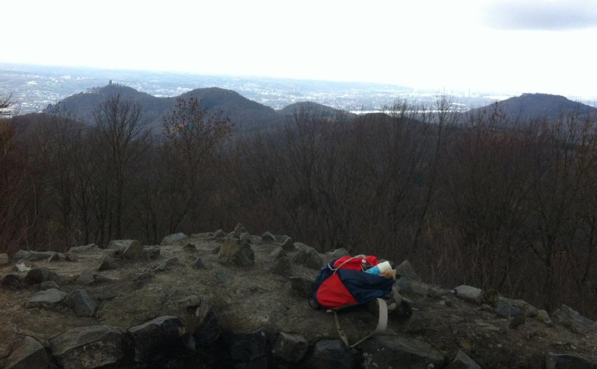 Rücksack liegt auf steinigem Untergrund, im Hintergrund sind Berge vor hellem Himmel zu sehen