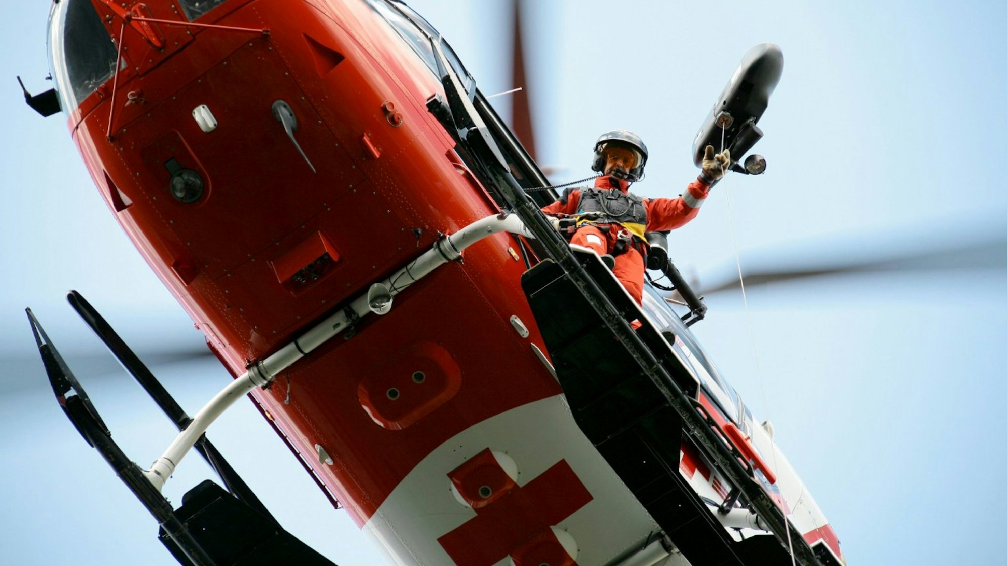 Bergretter schaut aus einem Helikopter.