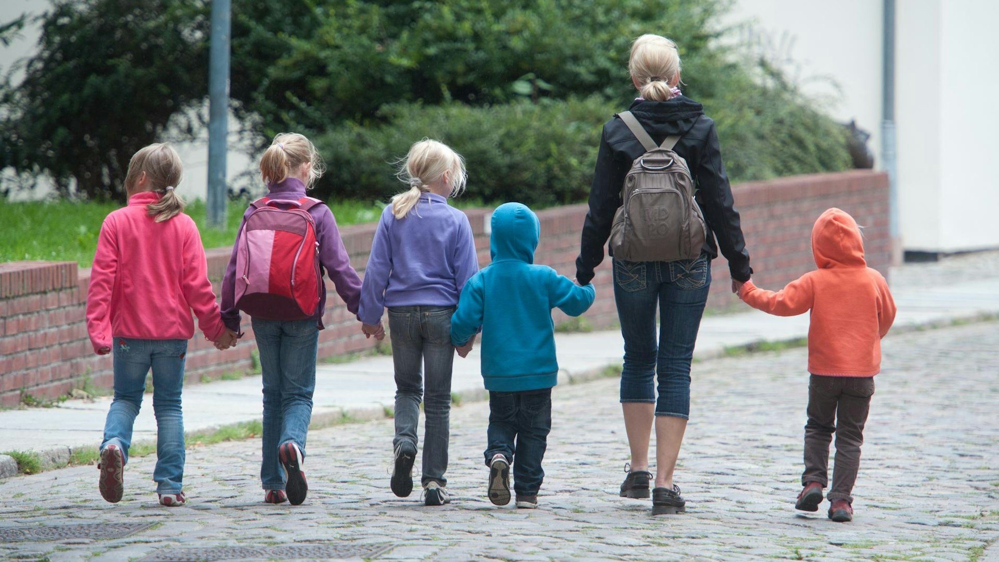 Das Foto zeigt eine Frau und fünf Kinder, die sich an den Händen halten.