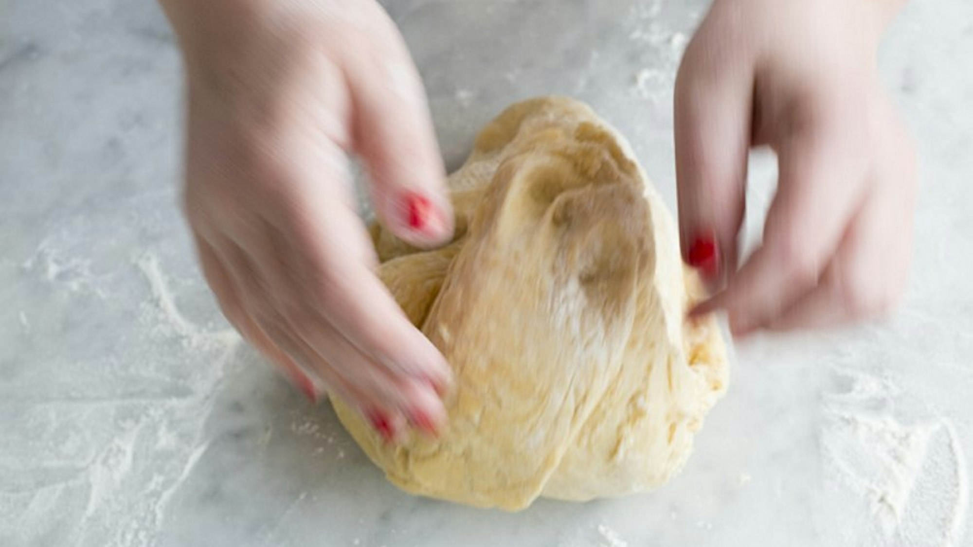 Der Hefeteig wird von Händen geknetet.