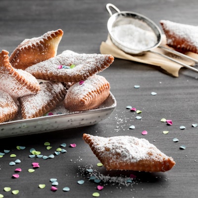 Mutzen mit Puderzucker in einer Schale, Konfetti liegt drumherum