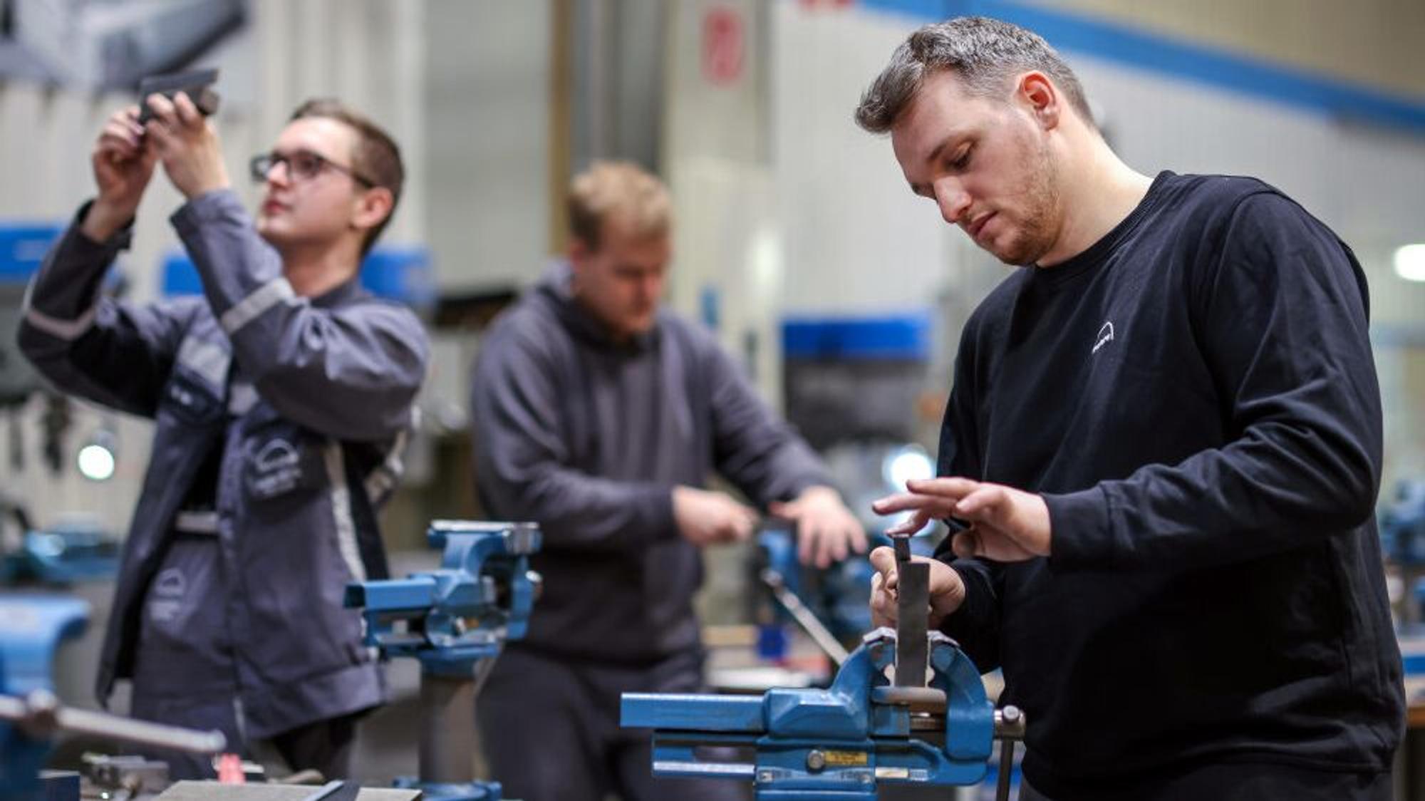 Junge Männer arbeiten an Maschinen.