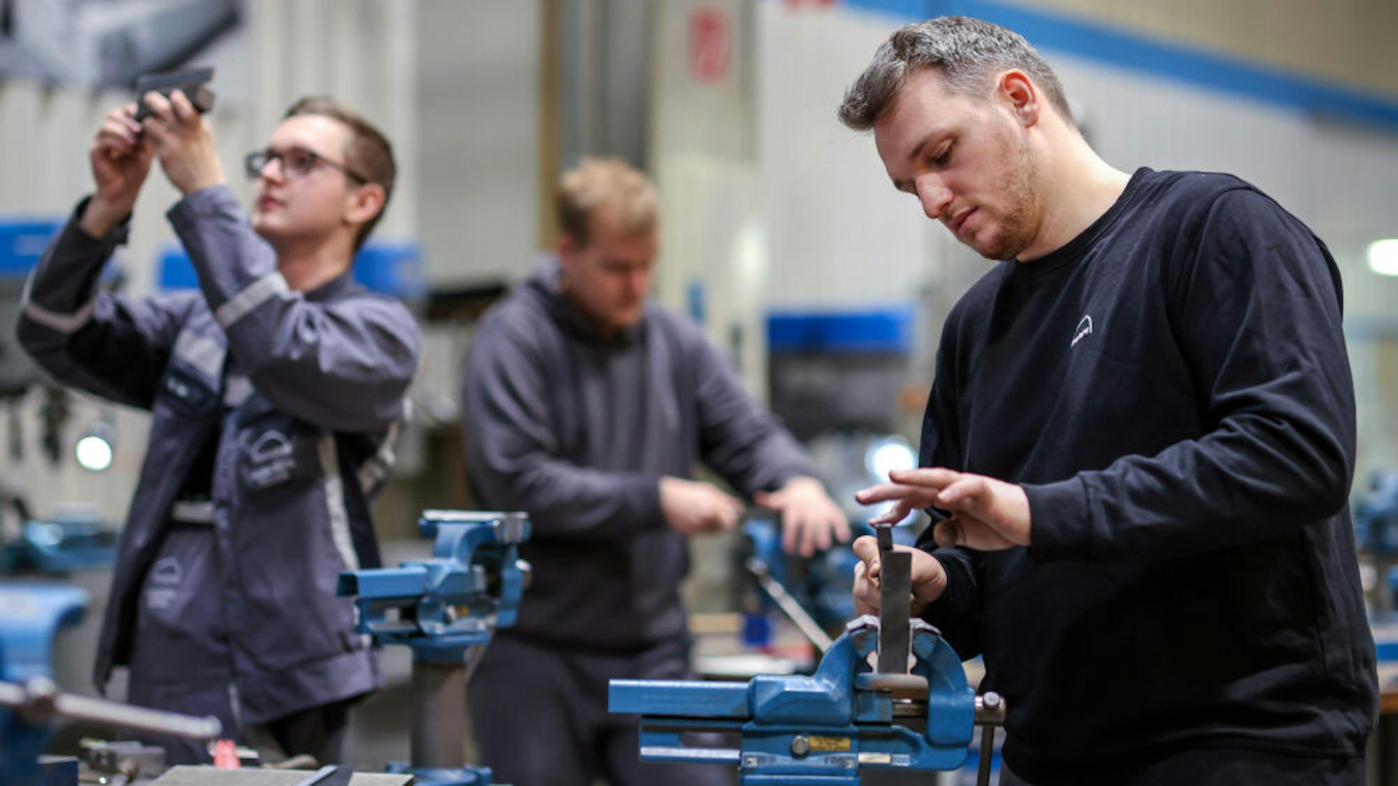 Junge Männer arbeiten an Maschinen.