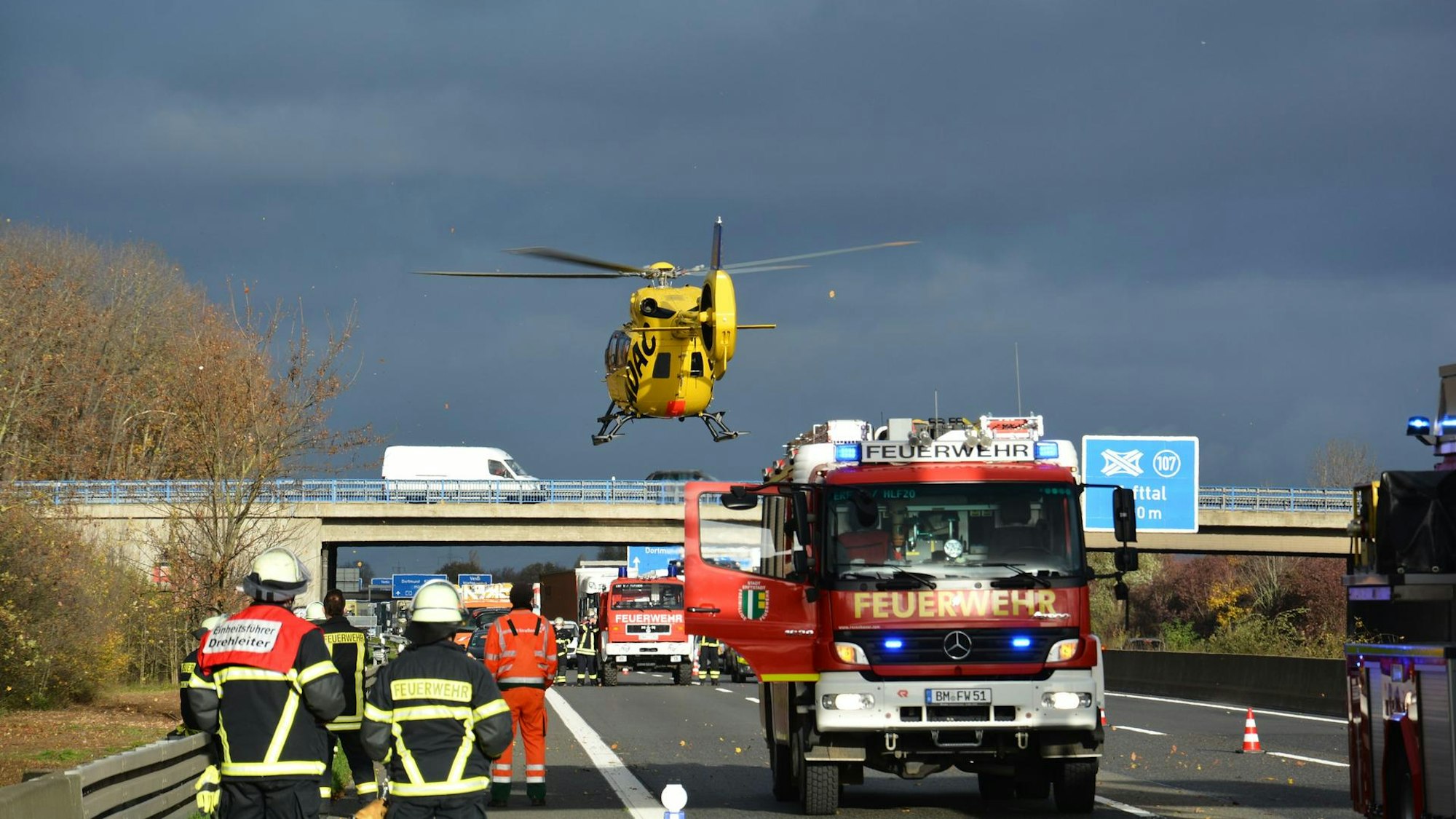 Ein ADAC-Hubschrauber landet hinter einem Feuerwehragen auf der Autobahn 1.