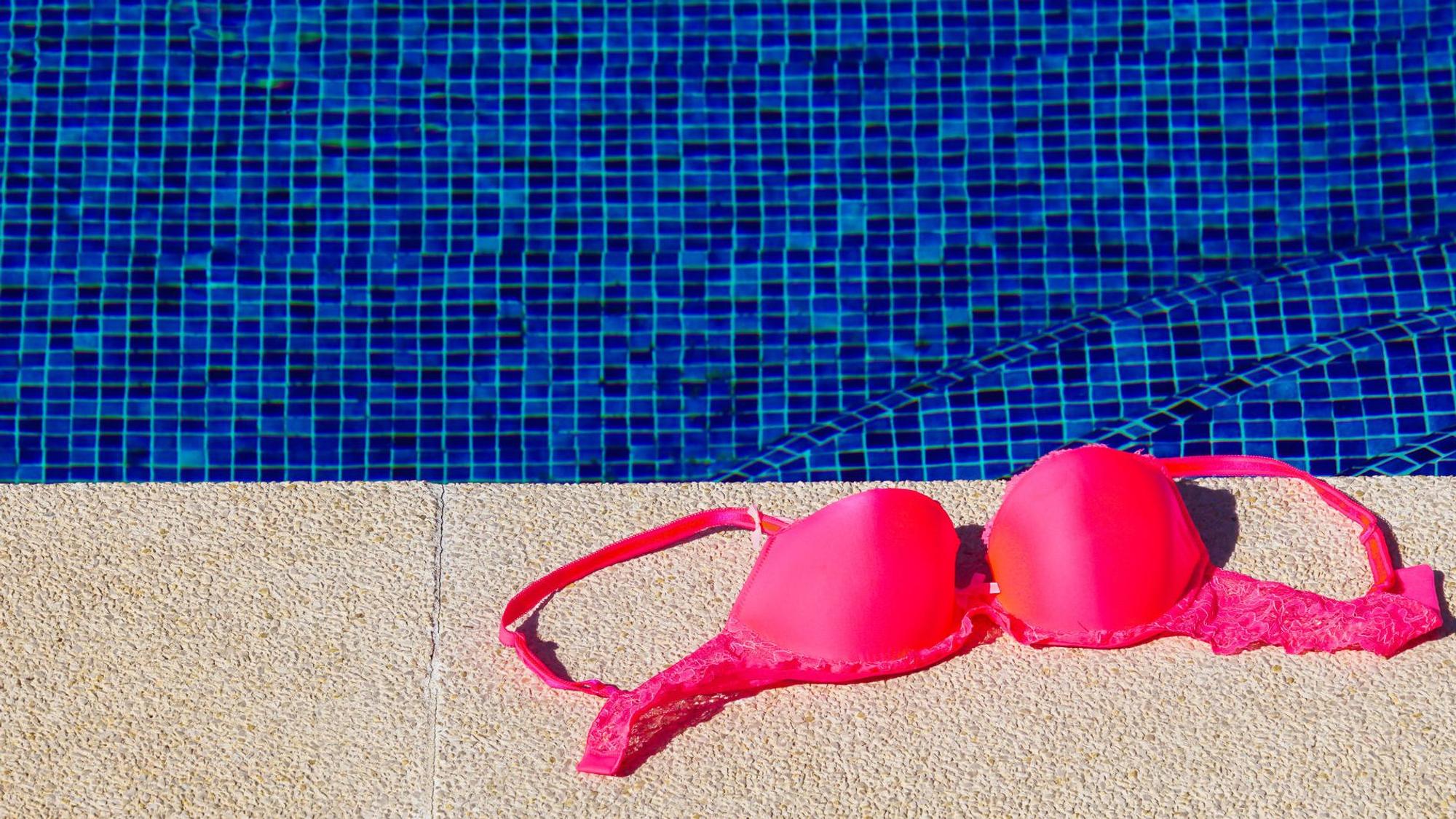 Ein Bikinioberteil liegt am Rand von einem Schwimmbecken.