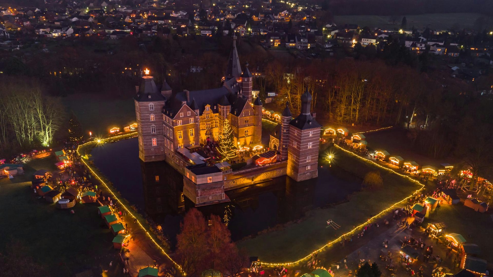 Luftaufnahme von Schloss Merode mit vielen Lichtern in der Nacht.