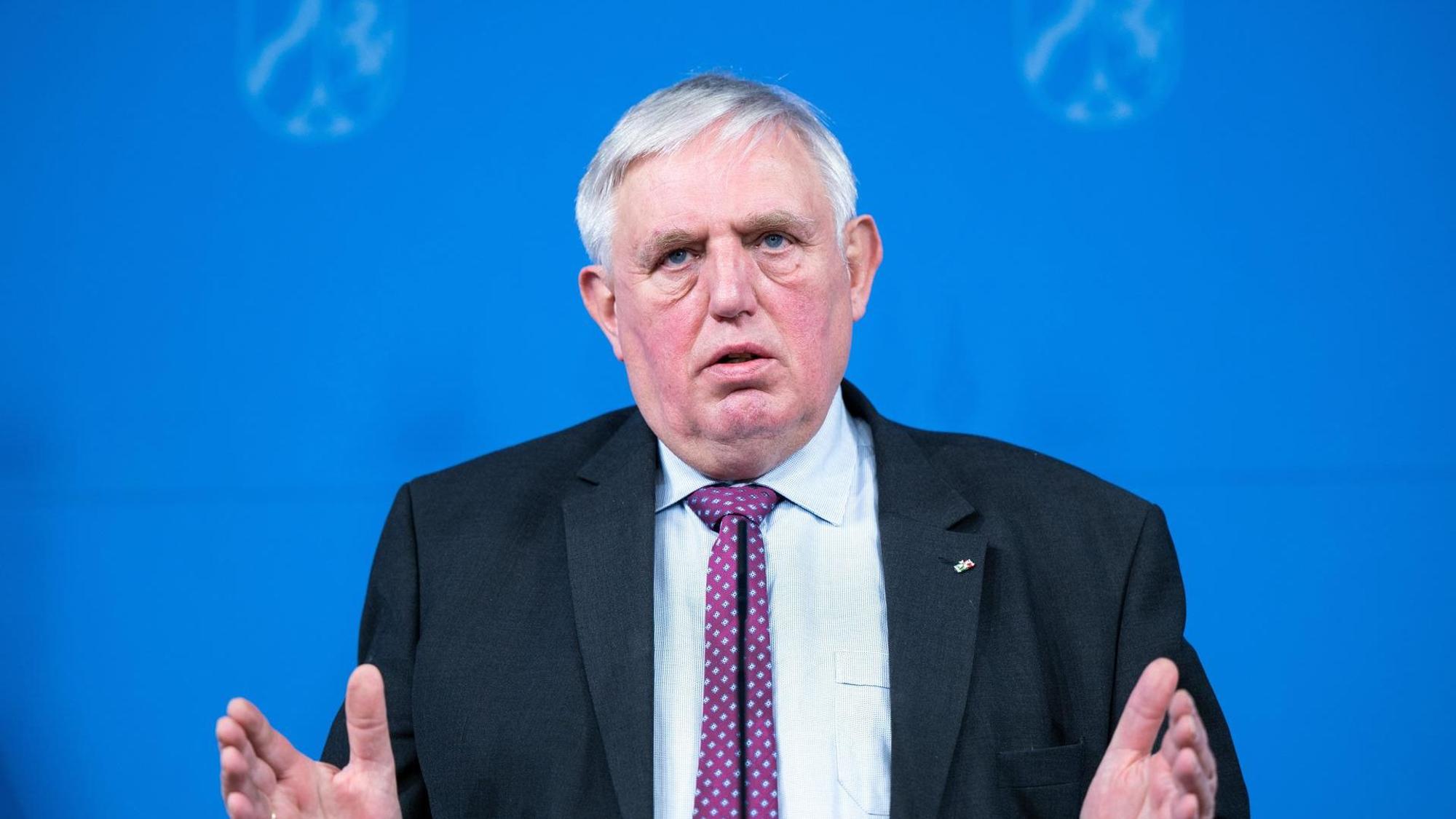 Karl-Josef Laumann spricht und steht vor einem blauen Hintergrund bei einer Pressekonferenz.