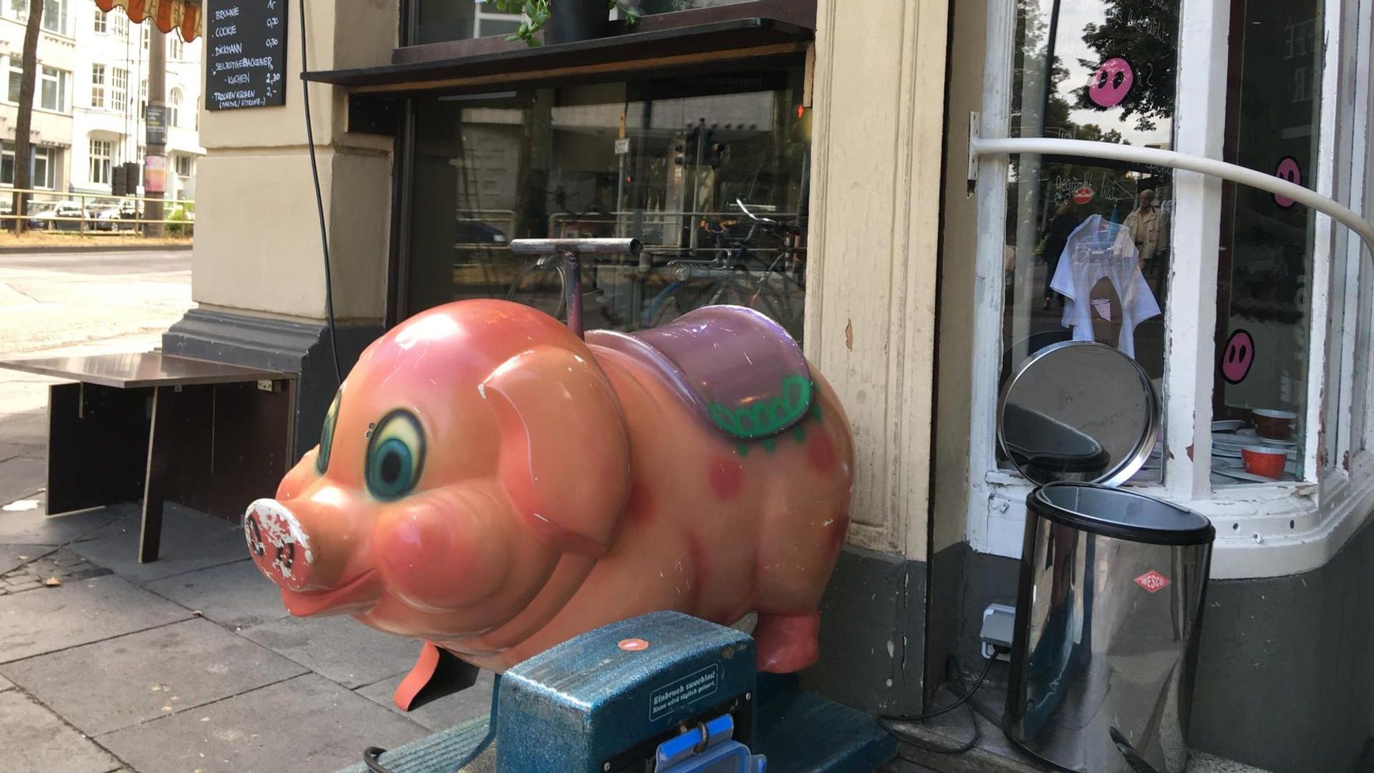 Ein kleines Schweine-Fahrgeschäft für Kinder vor der Caffé Bar