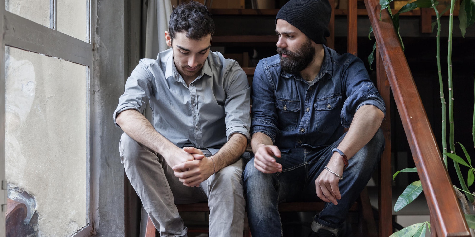 Zwei Männer sitzen auf einer Treppe und unterhalten sich.