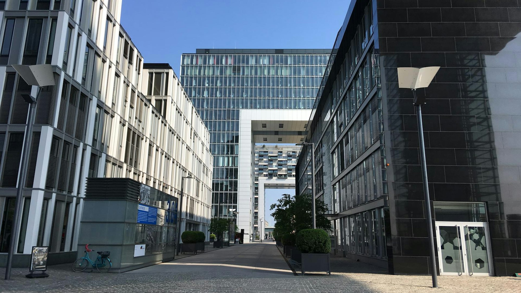 ein Weg führt zwischen modernen Häusern hindurch, im Hintergrund die Kranhäuser im Rheinauhafen