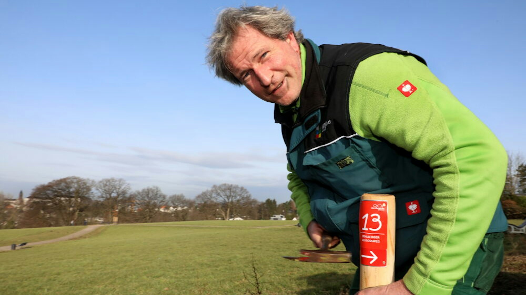 Wanderland-Wegemanager Wastl Roth-Seefrid haut mit einem Hammer einen Pflock für den Bensberger Schlossweg in den Boden.