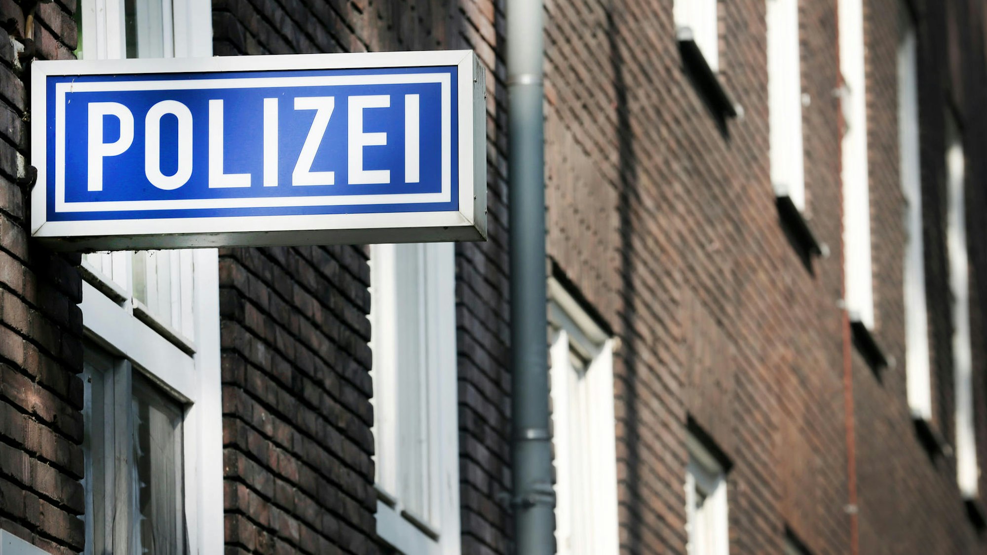 Die Polizeiwache in Mülheim/Ruhr: Die Backstein-Fassade ist zu sehen, daran montiert ein blau-weißes Schild mit der Aufschrift Polizei.