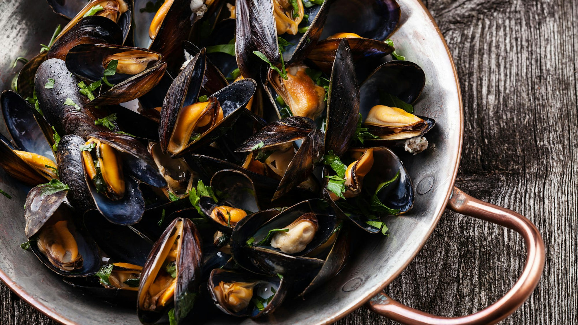 Gekochte Muscheln in einem Topf stehen auf dem Tisch.