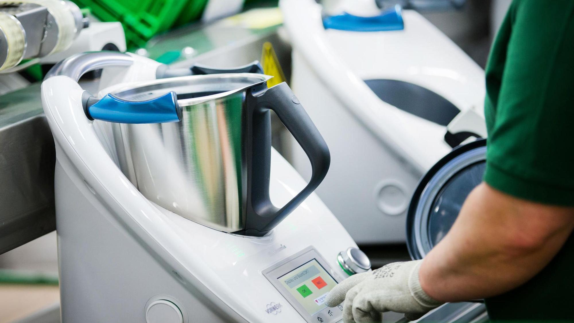 Mehrere Thermomix-Küchengeräte mit silbernen Töpfen in weißen Plastikgehäusen stehen nebeneinander.