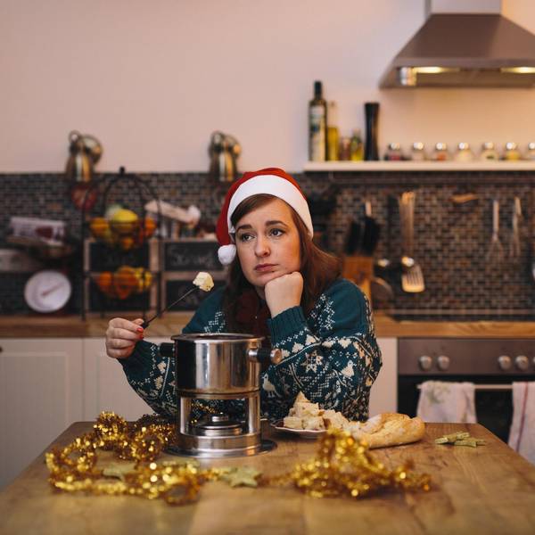 Die Autorin sitzt mit winterlichem Pullover und Nikolaus-Mütze allein am Küchentisch und isst Käse-Fondue.
