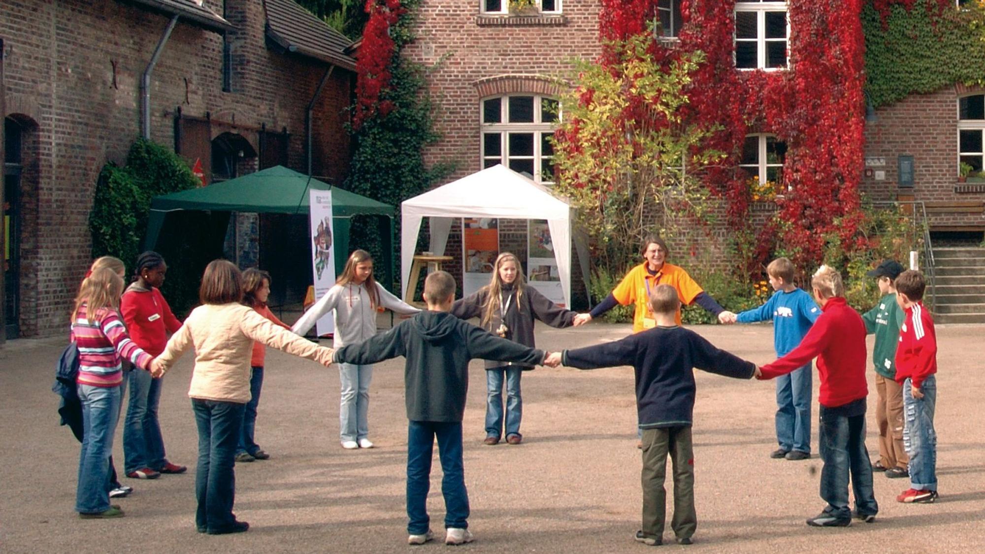 Kinder stehen im Kreis in einem Innenhof