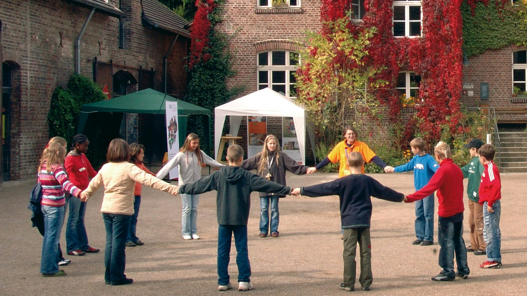 Kinder stehen im Kreis in einem Innenhof