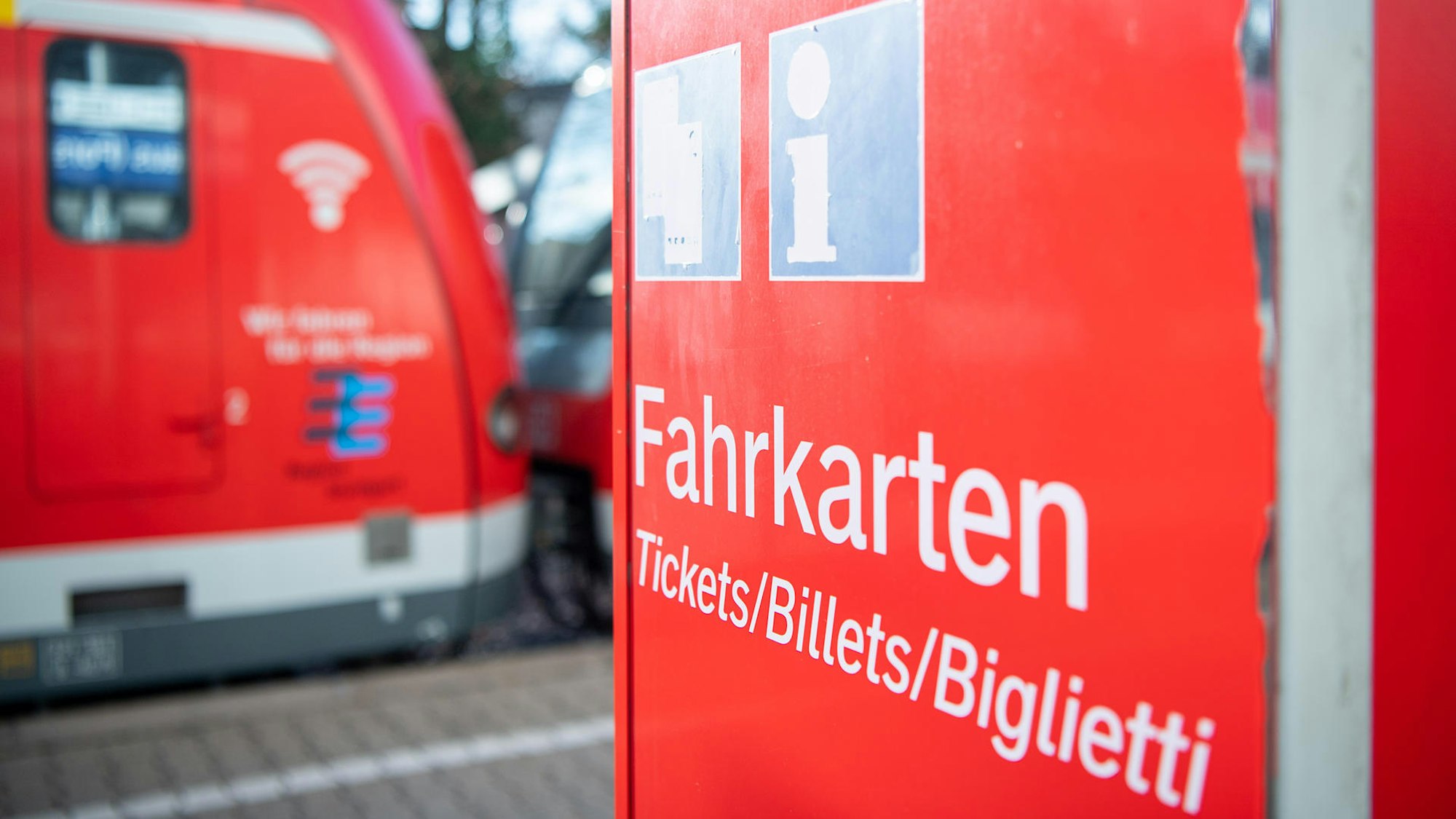 Ein Fahrkarten-Automat der Deutschen Bahn. Im Hintergrund ist ein Regionalzug zu sehen.