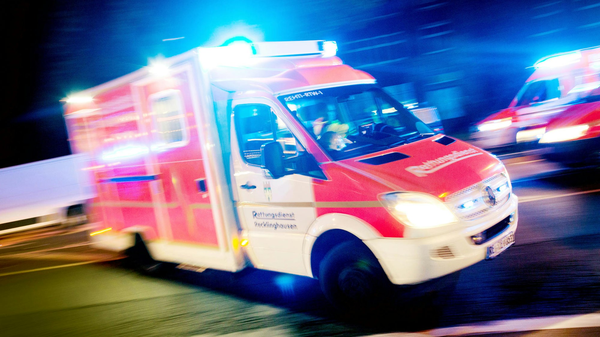 Ein Rettungswagen ist mit Blaulicht auf der Straße unterwegs.