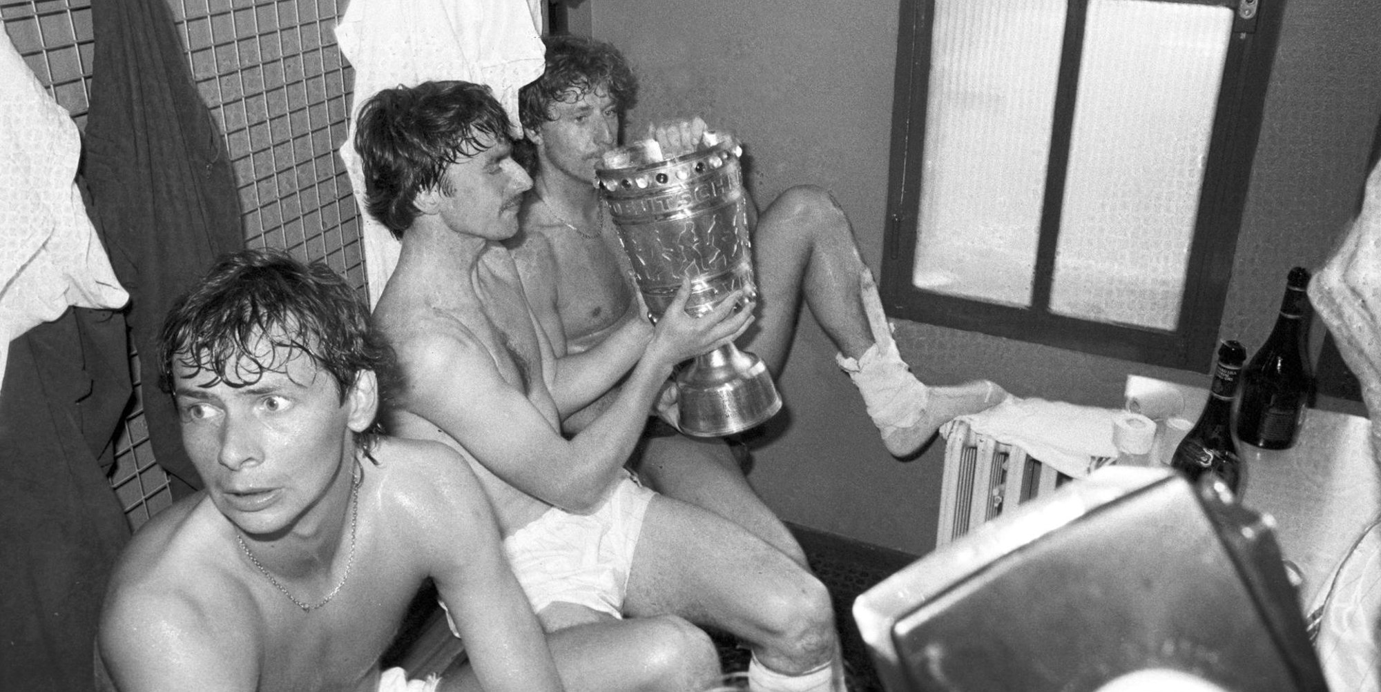 Das Foto zeit Klaus Allofs (M.) und Toni Schumacher nach dem Pokalsieg im Finale 1983 über Fortuna Köln in der Umkleidekabine des Müngersdorfer Stadions.