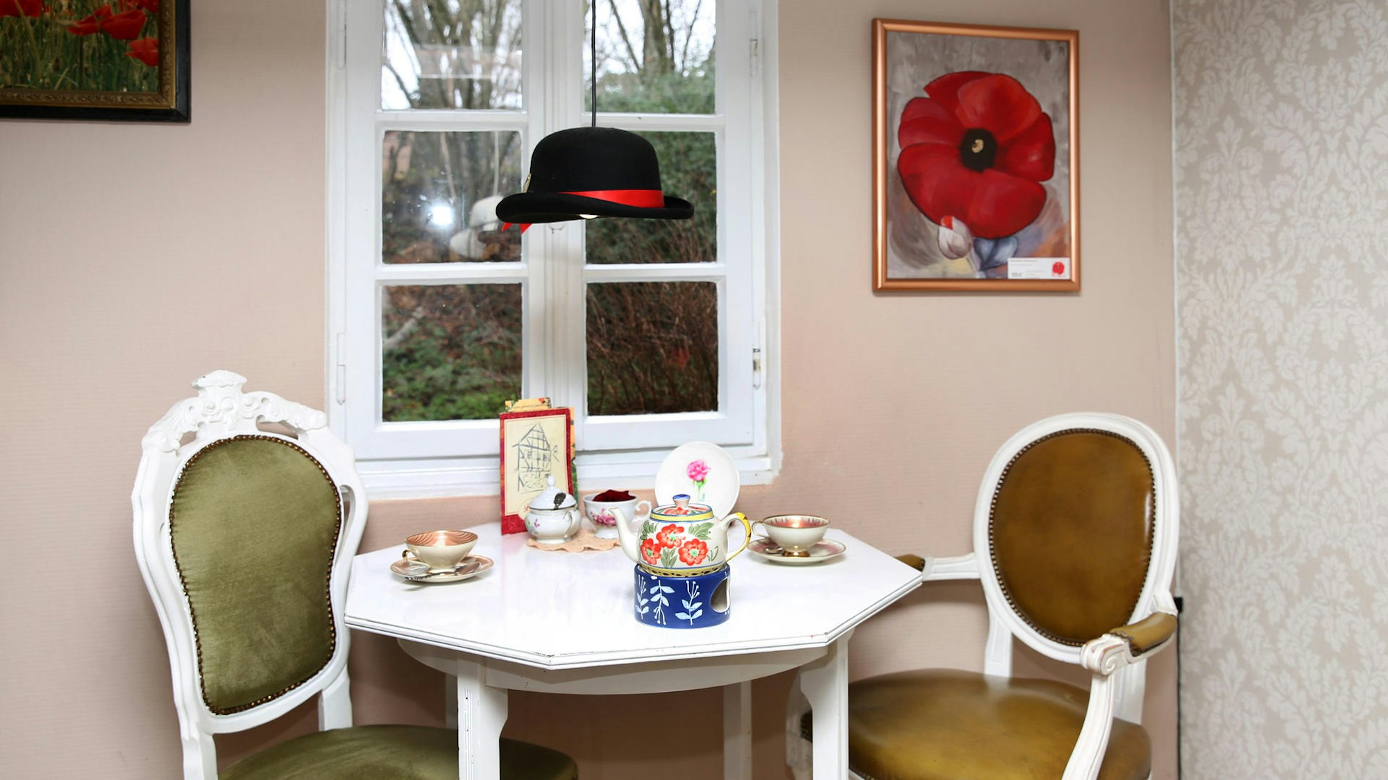 zwei Polsterstühle an einem Tisch mit bunt gemustertem Kaffeegeschirr