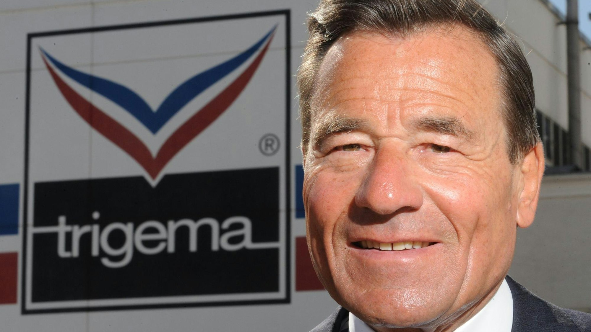 Wolfgang Grupp steht vor dem Trigema-Logo.