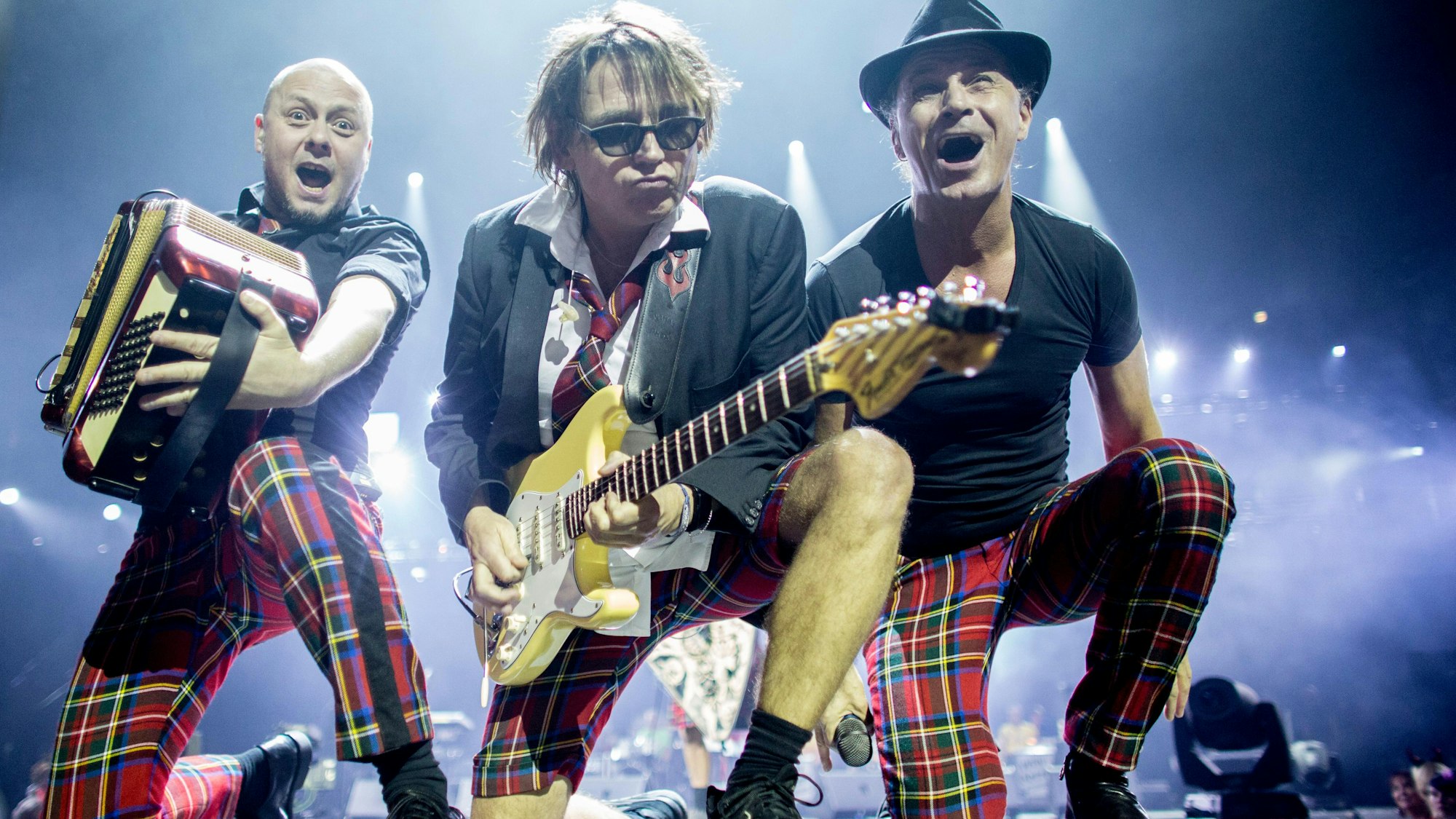 Kai Engel (l.), Harry Alfter und Peter Brings (r.) knien während eines Auftritts auf den Knien