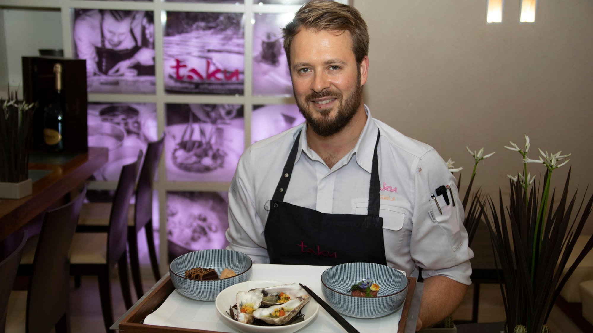Sternekoch Mirko Gaul mit einem Tablett und Gerichten