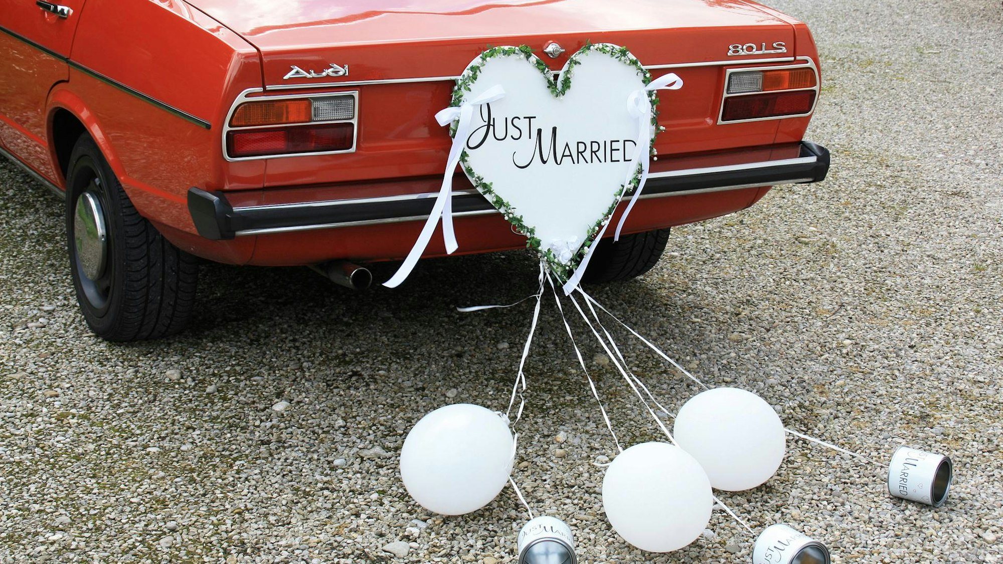Ein Auto mit einem „Just Married“-Schild und Luftballons.