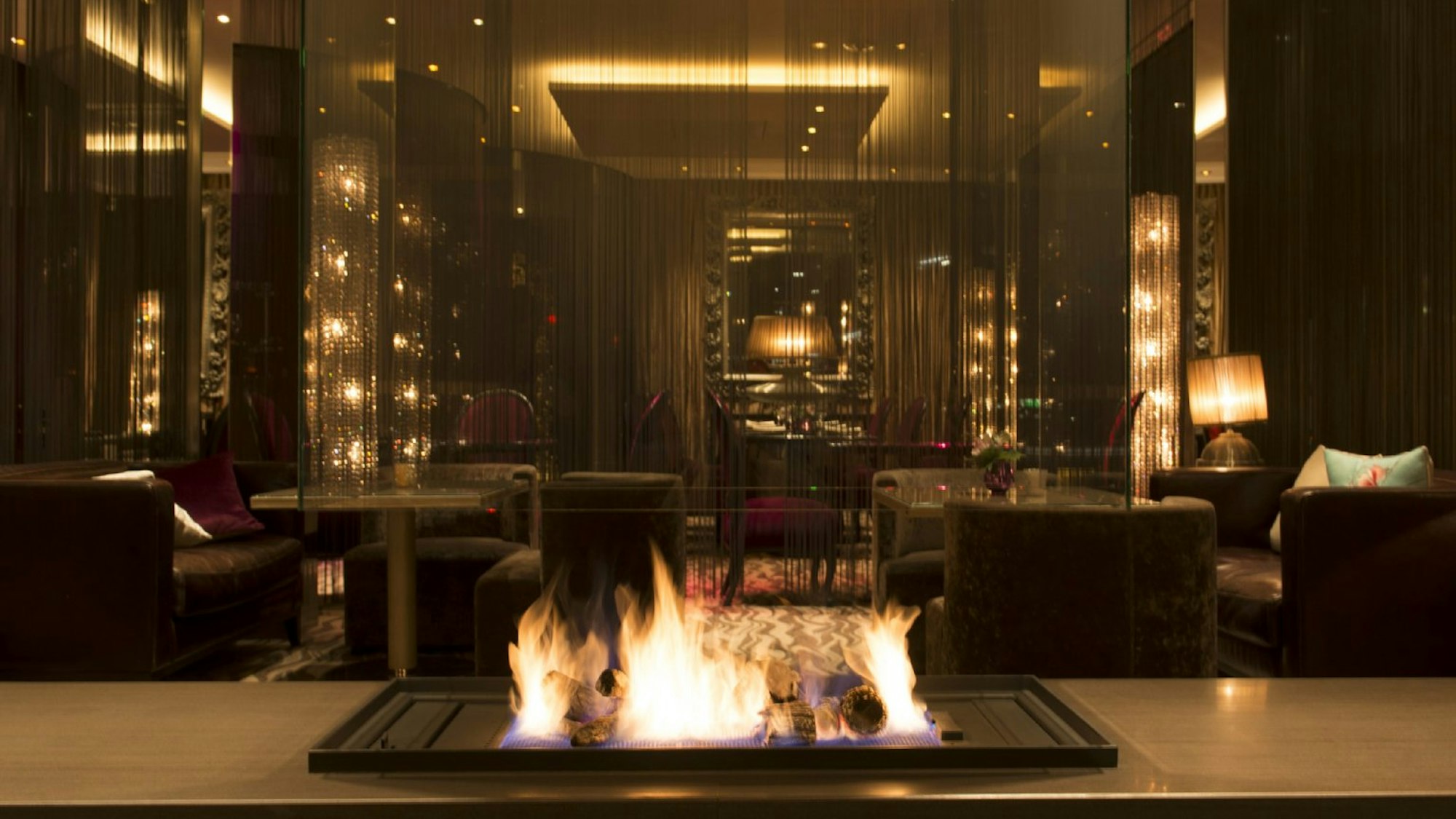 Offener Kamin im Savoy Hotel, dahinter sind plüschige Sitzgelegenheiten zu sehen.