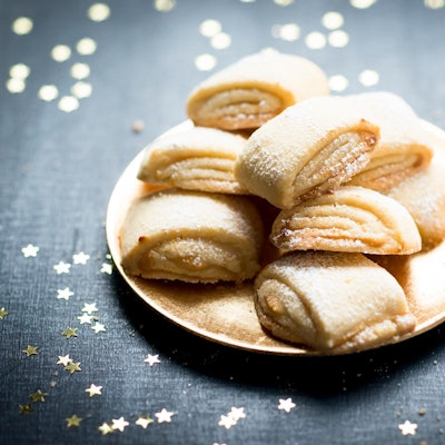 Zuckrige Marzipanballen liegen auf einem Teller angerichtet, rundherum sind goldene Sternchen verteilt