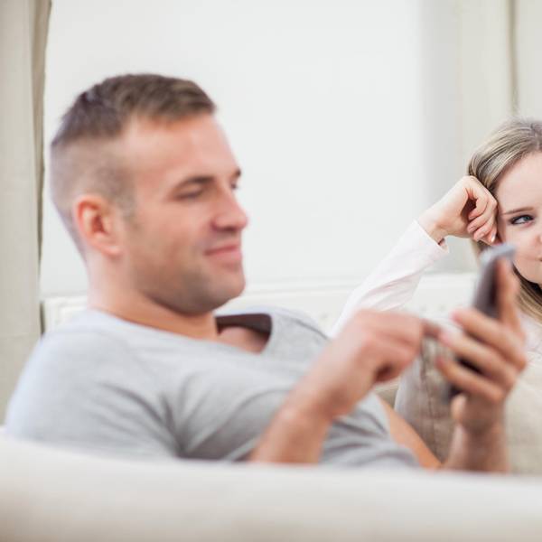 Mann und Frau sitzen auf der Couch: er dattelt, sie ist genervt