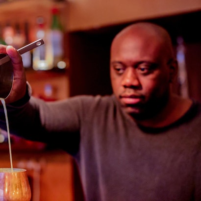 Barchef Samuel Antonio-Bernardo gießt Flüssigkeit in ein Cocktailglas.
