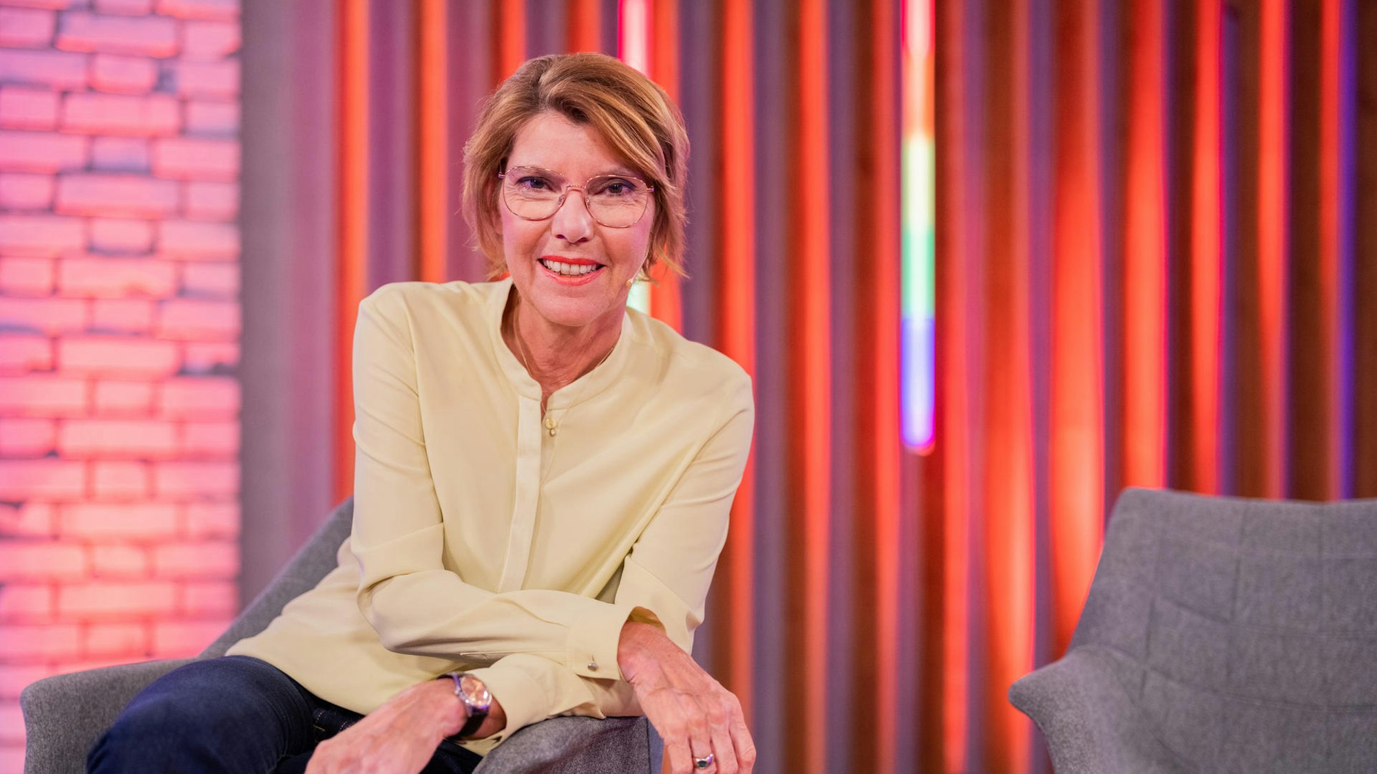 Bettina Böttinger sitzt auf einem Sessel.