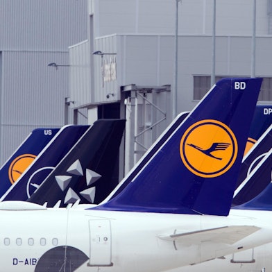 Flugzeuge der Lufthansa stehen auf einem Flughafen.