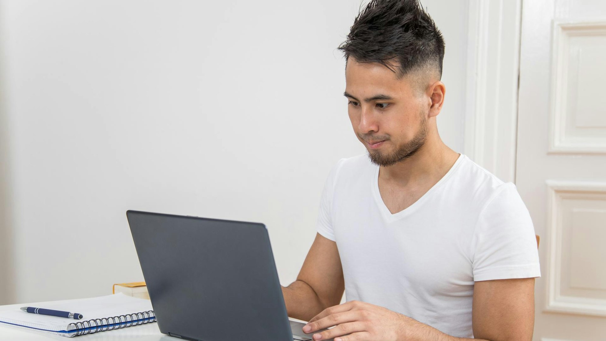 Junger Mann sitzt vor seinem Laptop.