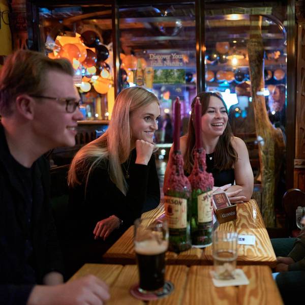 Fünf junge Menschen sitzen in einer Kneipe am Tisch.
