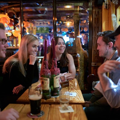 Fünf junge Menschen sitzen in einer Kneipe am Tisch.