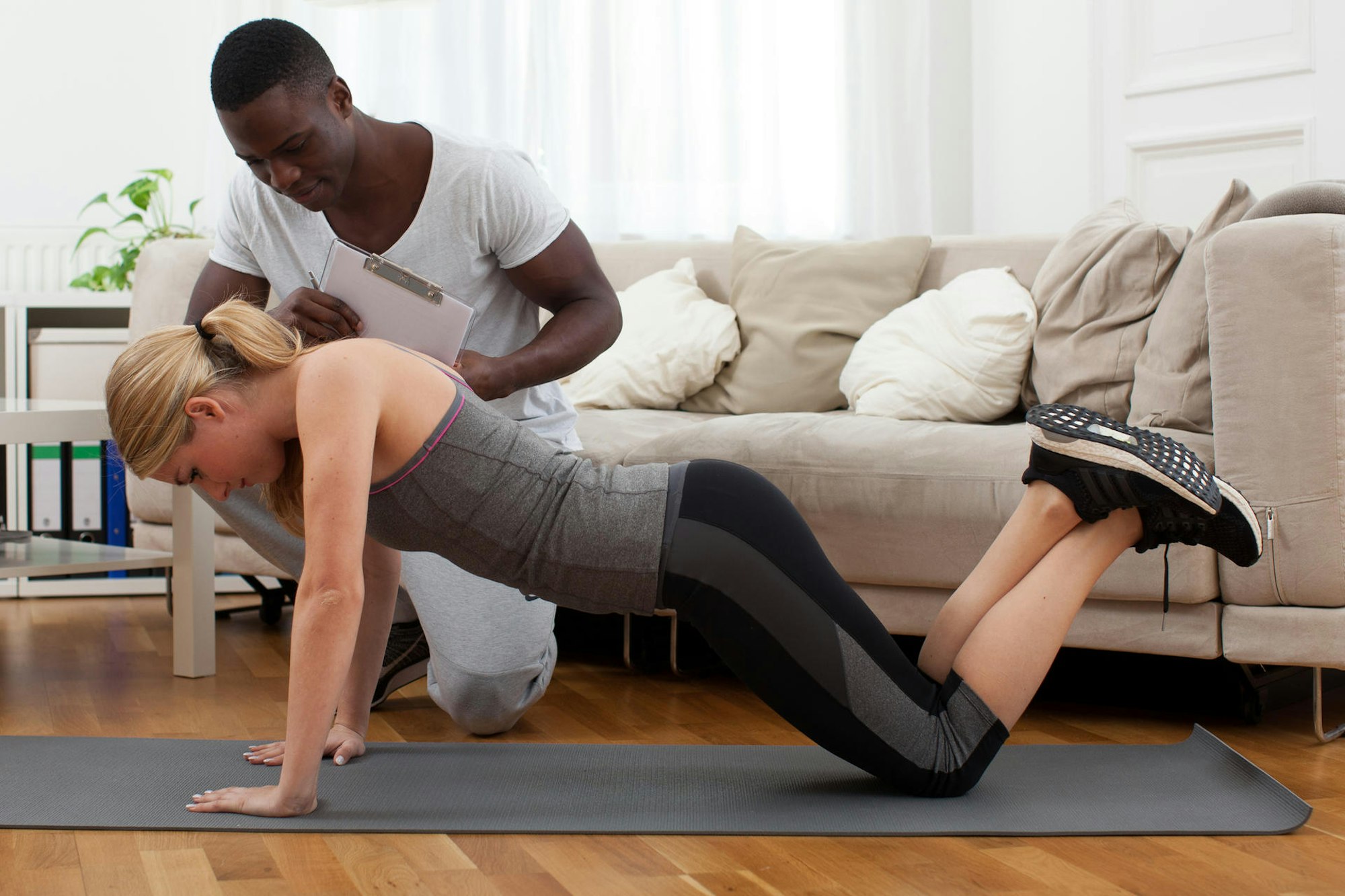 Frau trainiert im Wohnzimmer und bekommt Hilfsstellung_Saubere Ausführung