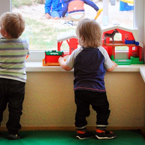 Zwei Kinder gucken in der Kita aus dem Fenster