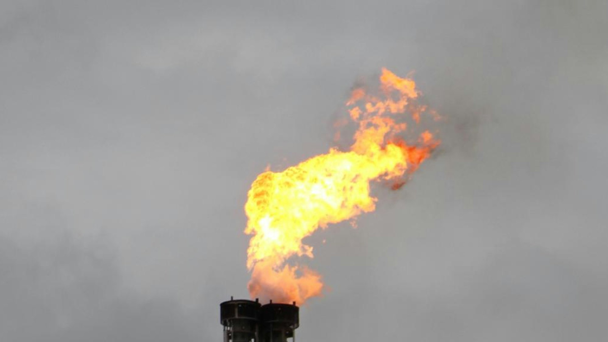 Das Foto zeigt eine Fackel vor grauem Himmel.