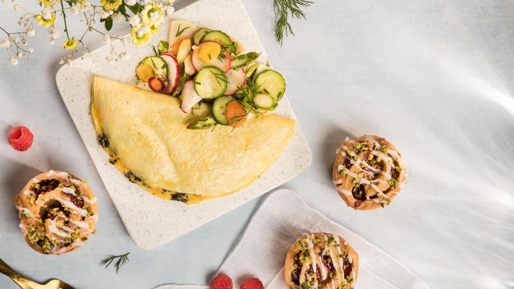 Ein lecker angerichtetes Omelette und Pistazienschnecken liegen angerichtet auf einer Platte