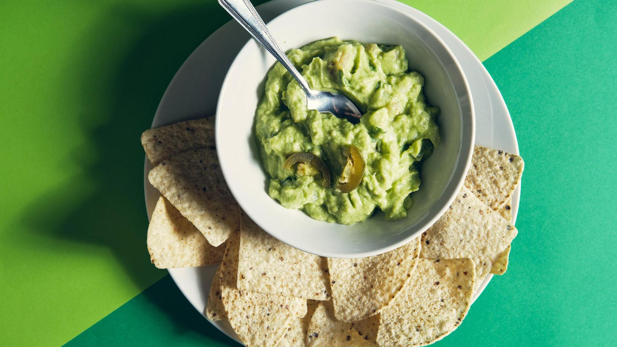 Gucamole in einer Schale, daneben Tortilla-Chips.