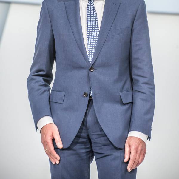 Bayer-Vorstandschef Werner Baumann steht im Anzug auf einer Bühne.