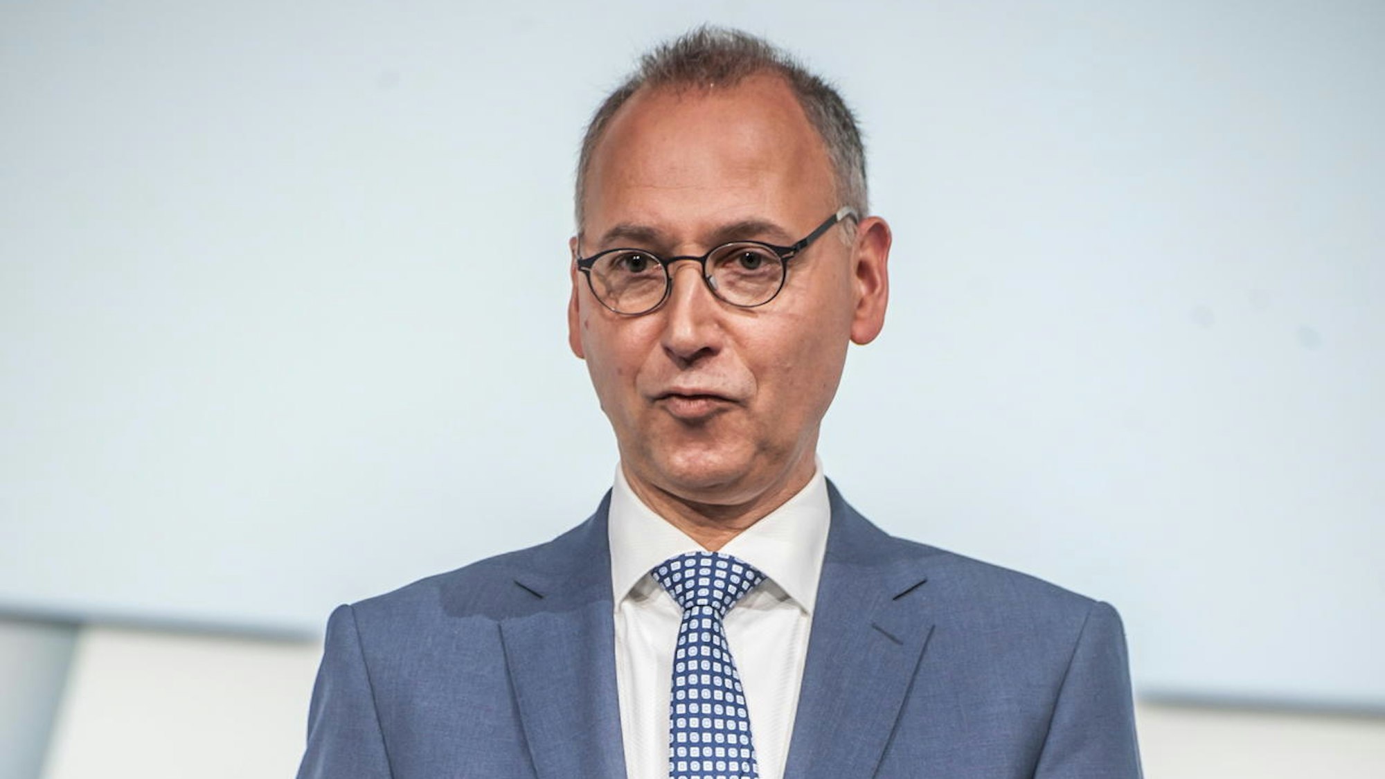 Bayer-Vorstandschef Werner Baumann steht im Anzug auf einer Bühne.